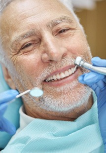 man smiling while dentist is cleaning teeth 