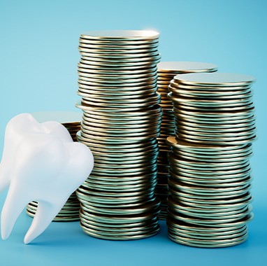 a model tooth next to a stack of coins