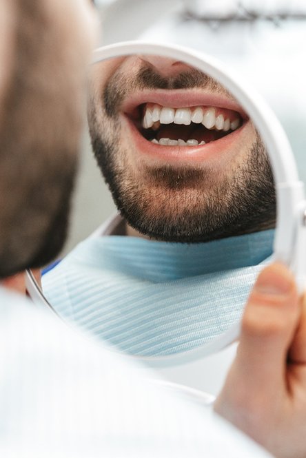 Man admiring the results of his dental work in mirror