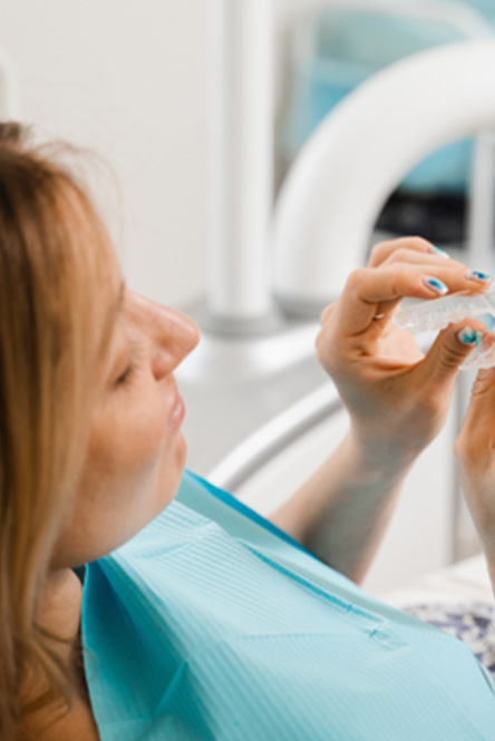 Patient in treatment chair holding clear aligner