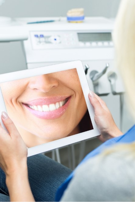 Woman looking at virtual smile design on tablet computer screen