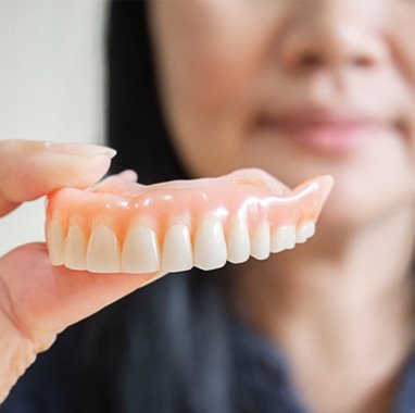 Woman holding dentures