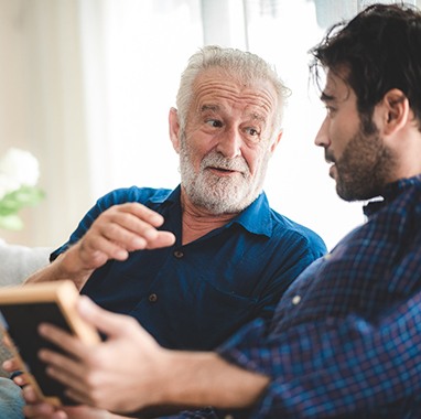 An older man talking with his adult son