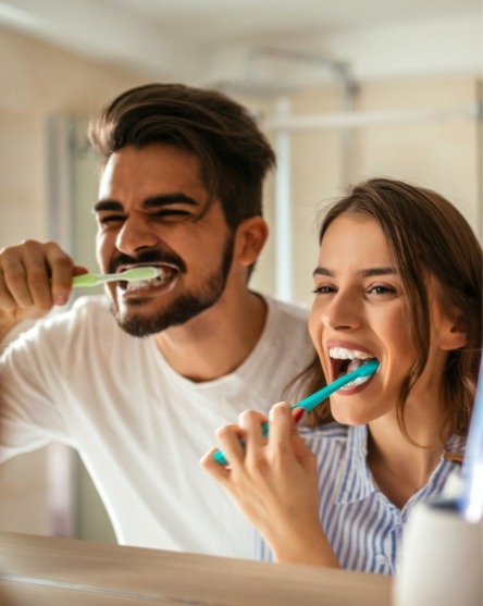 Man and woman brushing teeth to prevent dental emergencies