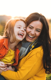 Smiling mother and child holding each other outdoors