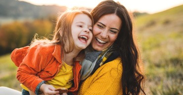 Smiling mother and child holding each other outdoors