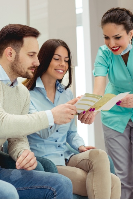 Dental team member and patients discussing dental insurance coverage