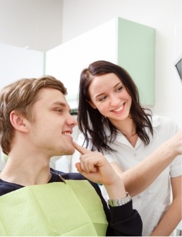 Dental team member talking to patient who is pointing to his smile