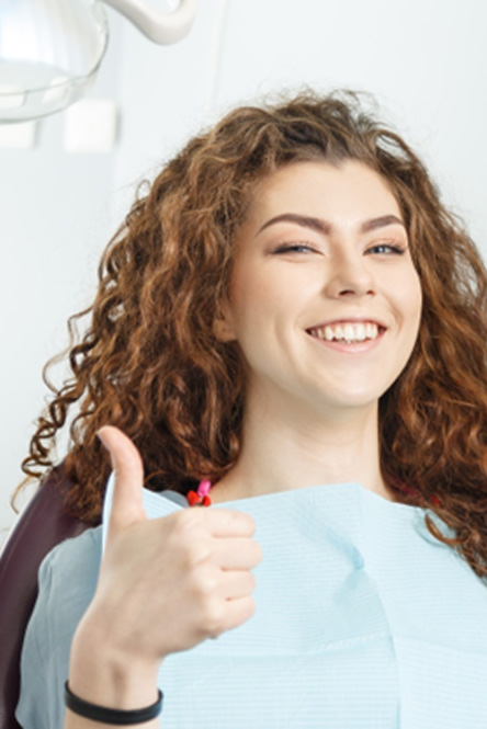 Female dental patient giving a thumbs up