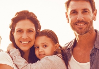 Parents and child smiling together after family dentistry
