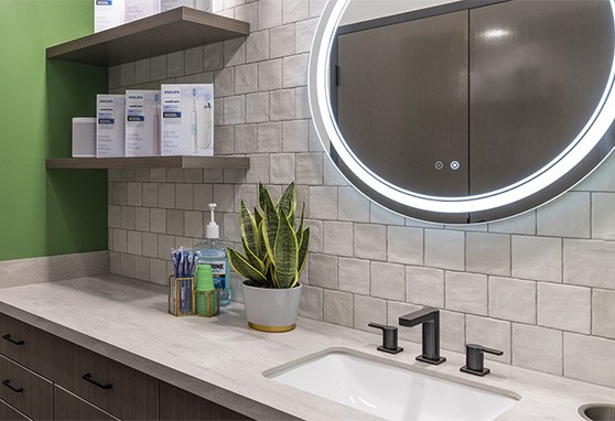 Sink and mirror with electric toothbrushes in packages on a nearby shelf
