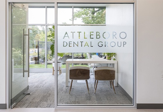 Attleboro Dental Group logo on the glass wall of a consultation room