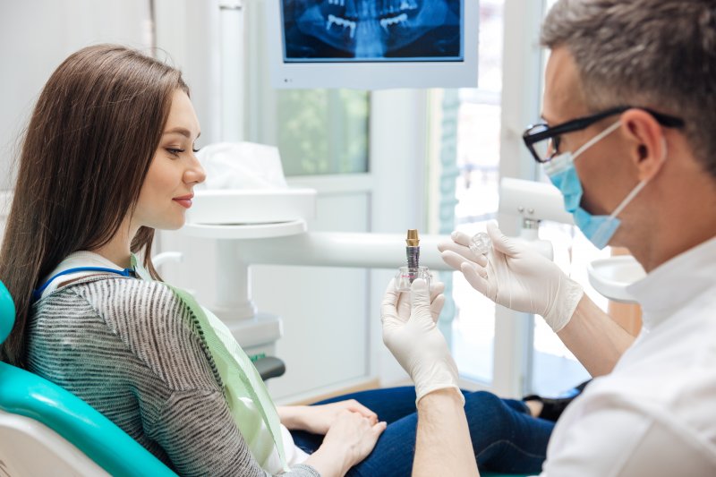 Dentist showing a patient a dental implant.