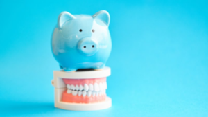 Blue piggy bank sitting on top of a wax model of teeth