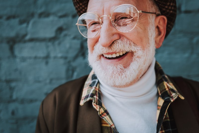 An old, cheerful, and bespectacled man smiling