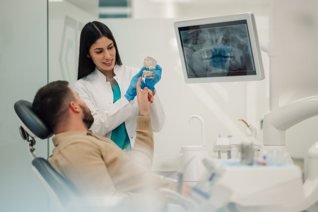 An endodontist showing a patient a model of an infected tooth